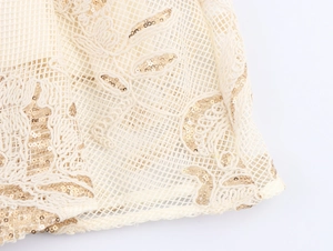 Detail of elegant beige mesh fabric with golden sequins and intricate floral embroidery