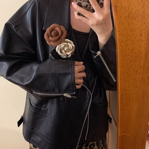 Elegant leather camellia brooches in brown and gold on a black leather jacket collar