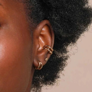 Detailed close-up of double-layered gold wave hoop earrings and ear cuff on a model