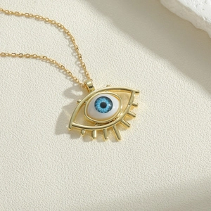 Macro detail of the golden Evil Eye pendant with blue iris and delicate eyelashes