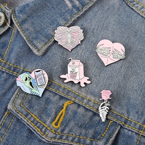 Détail de l'ensemble de pin's tête de mort rose et brique de lait sur veste en jean