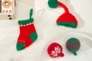 Close-up of knitted Christmas ornaments featuring mini socks, hats, and balls in festive colors