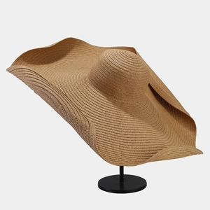Wide brim woven straw sun hat for women on black stand for beach vacation sun protection