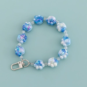 Blue and white gradient cat paw bead keychain with silver hook on a light blue background