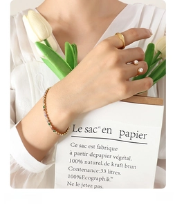 Detailed shot of gold rings and a colorful tennis bracelet styled with white tulips