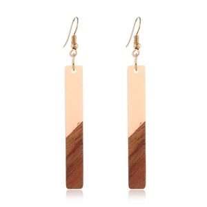 Détail de boucles d'oreilles pendantes en bois et résine avec crochets dorés et reflet