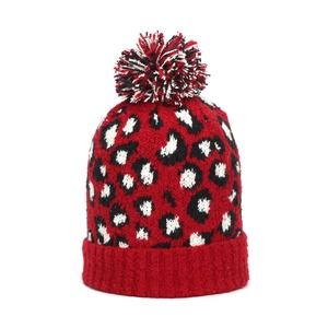 Close-up of leopard pattern knitted beanie with fluffy pompom and ribbed cuff
