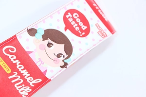Close-up of cute red caramel milk carton pencil case with a smiling cartoon girl