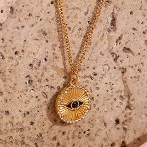 Macro shot of 18K gold plated evil eye coin pendant with black stone and white crystals