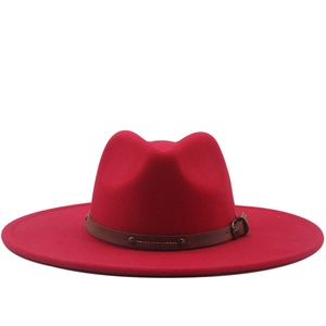 Detail of red fedora hat featuring a brown leather band with metallic studs and buckle