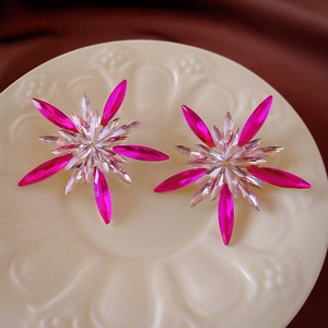 Macro detail of starburst earring with magenta and clear rhinestones on a decorative tray