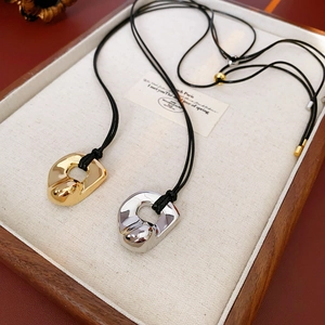 Macro view of gold and silver irregular liquid metal pendants on black rope necklaces