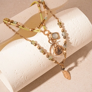Close-up of bohemian layered necklace with butterfly coin charm and green beads