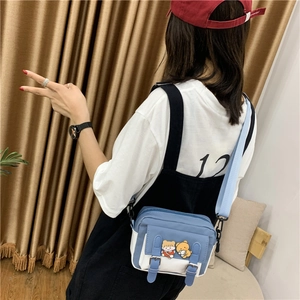 Detail of blue and white nylon crossbody bag featuring cute cartoon bear embroidery