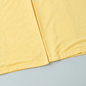 Detail of lemon yellow knit fabric showing the side slit and double-needle stitching