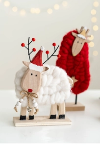 Detail of wool felt sheep Christmas ornament with wooden legs and festive red hat