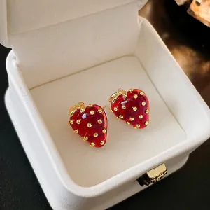 Sweet red strawberry stud earrings with gold leaves in a white velvet jewelry box
