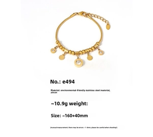 Detail of gold snake chain bracelet featuring zircon charm and Roman numeral disk pendant