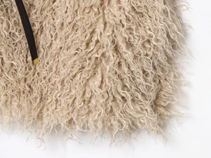 Detailed macro view of beige faux fur texture with black leather trim and golden buckle