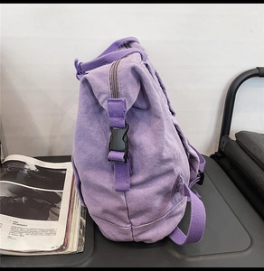 Side view of purple canvas backpack with black plastic buckle and adjustable strap detail