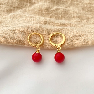 Detailed close-up of 18K gold-plated earring hoops featuring elegant red pearl drops