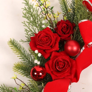 Christmas wreath with red roses, festive ornaments and ribbon for front door decor
