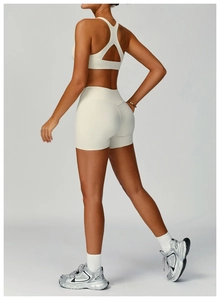 Close-up of cream high-waisted fitness shorts and cross-back sports bra on female model