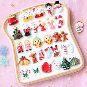 Detailed view of colorful Christmas resin charms like Santa and snowman on a white tray