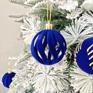 Gros plan de boules de Noël en velours bleu ajouré sur une branche de sapin enneigée