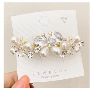 Close-up of butterfly hair clip featuring white pearls and sparkling crystal details