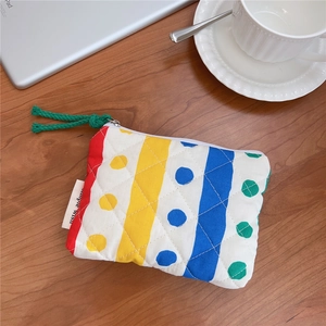 Detailed close-up of a quilted floral mini coin purse with colorful stripes and green knot