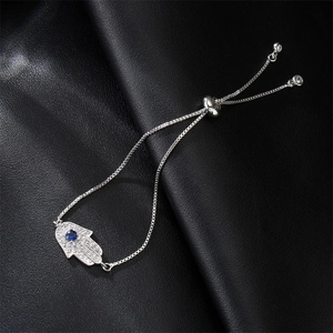 Silver Hamsa Hand bracelet with blue cubic zirconia on black leather background