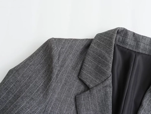 Close-up of lapel and shoulder of a dark grey pinstripe wool blend blazer with neat stitching
