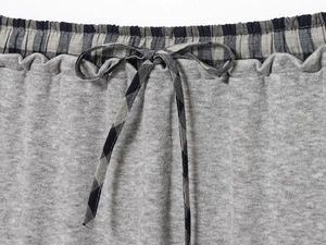 Close-up of gray knit pants waist with a black and white checkered drawstring tie