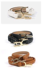Close-up of three narrow women belts in white, black and brown with gold metal buckles