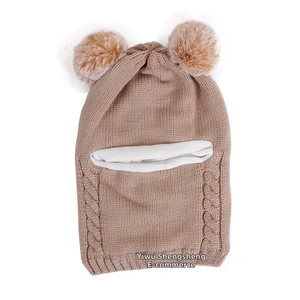 Detail of baby winter knit hat with dual fur pom-poms and thick twist weave texture