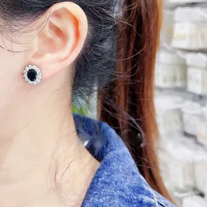 Close-up of elegant flower stud earring with black oval stone worn on the ear