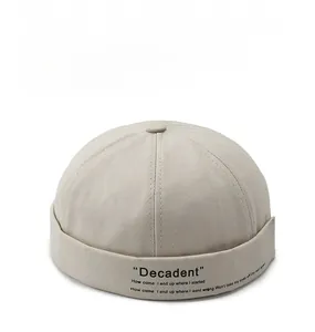 Detailed view of beige cotton skull cap featuring black Decadent letter embroidery