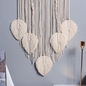 Detailed view of hand-woven beige cotton tapestry with macrame leaves and wooden beads