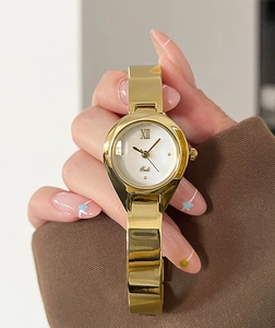 Detail of a luxury gold bangle watch with a white dial and Roman numeral XII on the wrist