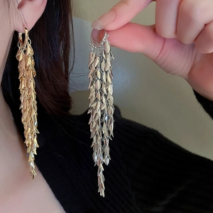 Detailed view of long leaf tassel earrings in gold and silver finish with metallic shine