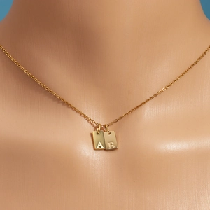 Detail of 18k gold plated square alphabet pendants A and B on a delicate chain necklace