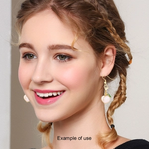 Close-up of model wearing cute pink heart-shaped enamel drop earrings with gold hooks