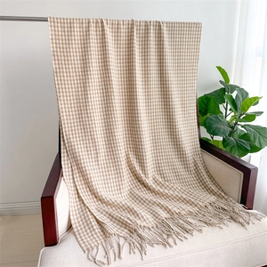 Detailed view of beige and white houndstooth scarf with elegant fringe on a wooden chair