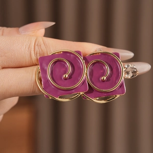 Close-up of vintage purple enamel square earrings with gold spiral design on model