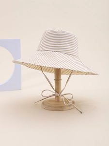 Detail of striped sun hat with wide brim and adjustable chin strap tie on a wooden stand