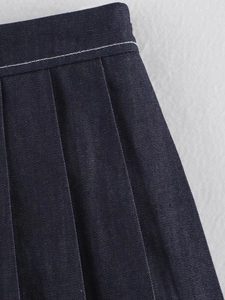 Dettaglio gonna a pieghe in denim blu scuro con cuciture bianche a contrasto in vita