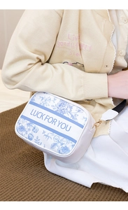 Detail view of the floral print shoulder bag featuring blue vintage patterns and metal hardware