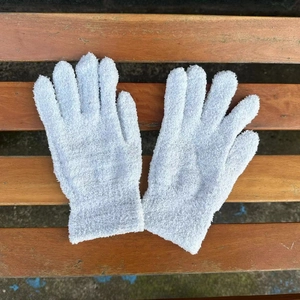 Close-up of soft white chenille knit winter gloves with elastic ribbed cuffs on a bench