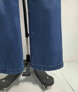 Detailweergave van de dubbele stiksels op de zoom van de donkerblauwe spijkerbroek